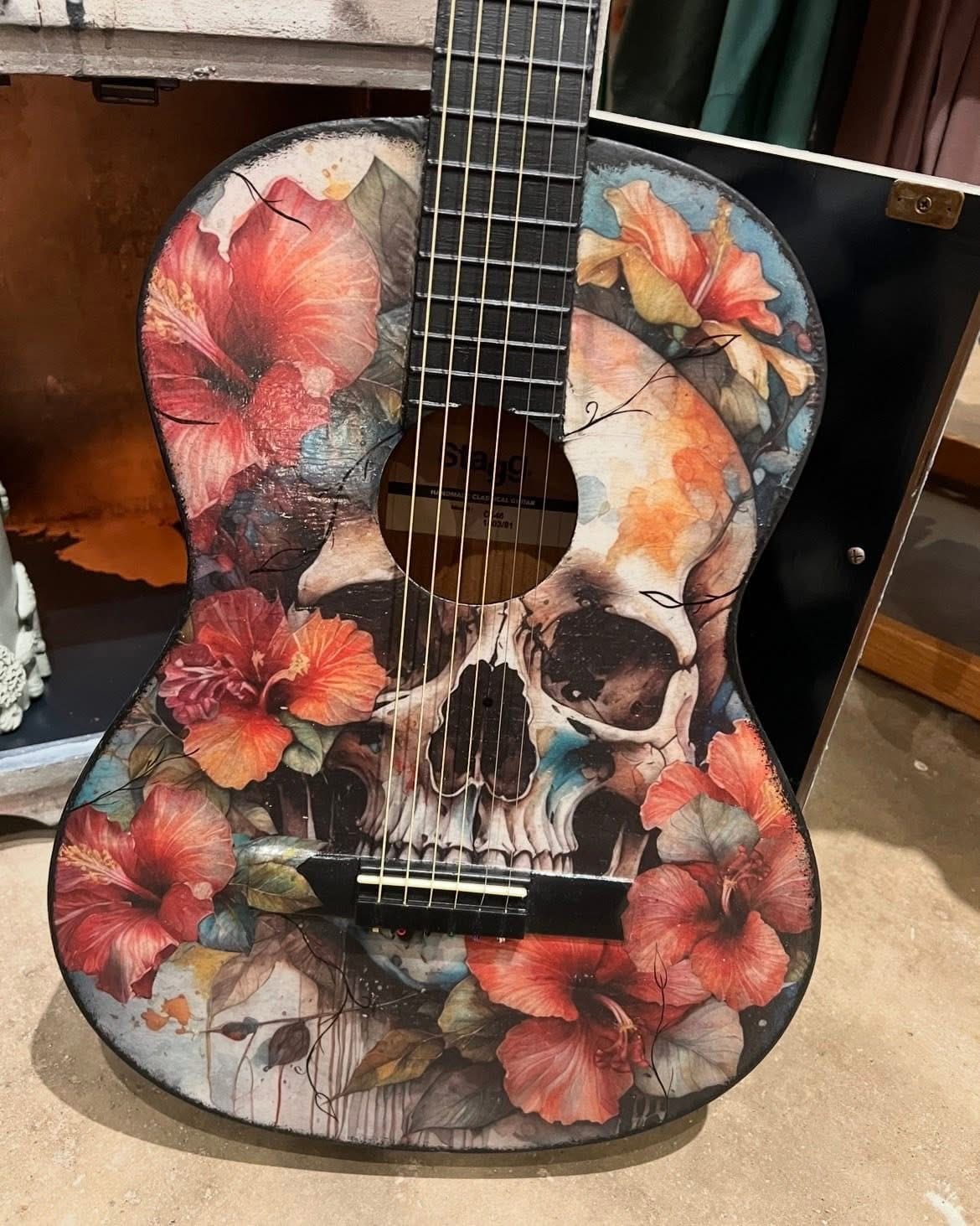 Guitar with skull and floral design on a wooden floor