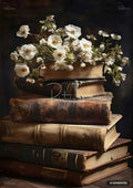 A tall stack of old, worn books with white flowers and green foliage arranged on the top book.