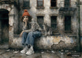 A young woman in an orange beanie, striped shirt, and jeans sits with a tabby cat on a ledge against a distressed building.